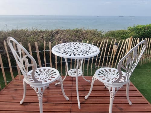 Chaises et table de bistrot blanc sur terrasse en bois avec vue sur la mer, gîte Bayeuzen, Saint-Côme-de-Fresné