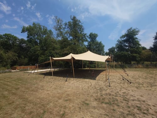 Cream stretch tent setup on sandy grounds at Domaine De Bafave, Périssac, with trees and fencing in background
