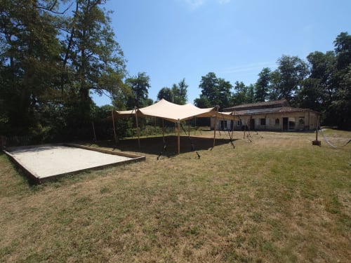 Domaine De Bafave outdoor event space with beige tent canopy, white platform, and rustic building in Périssac