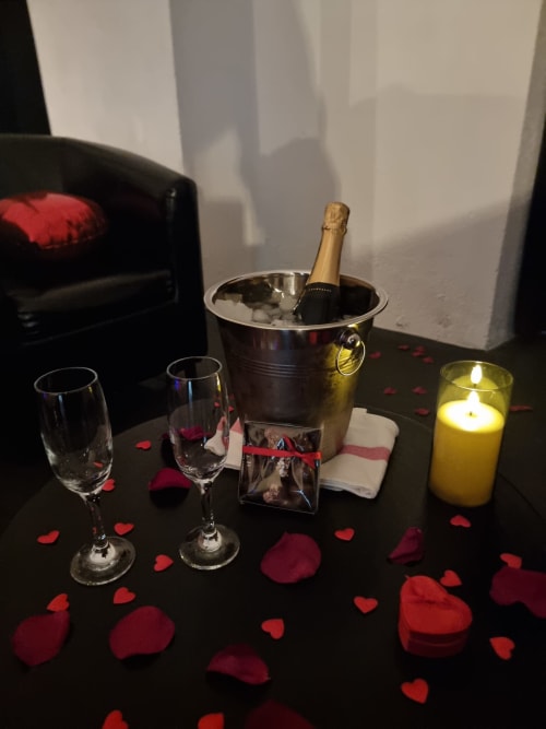 Ambiance romantique dans l'appartement Le Baldaquin au Bayeuzen B&B avec champagne, bougies et pétales de roses