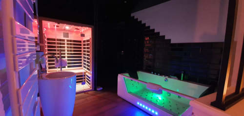 Salle de bains spa moderne à la Bayeuzen B&B avec sauna illuminé, bain d'hydromassage néon et TV écran plat à Bayeux, France