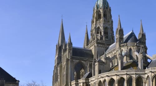 Architecture gothique de la cathédrale de Bayeux avec ses flèches pointues sur fond de ciel bleu, monument emblématique près du gîte Bayeuzen