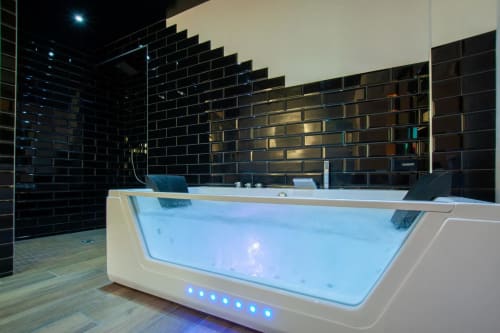 Baignoire spa moderne avec éclairage bleu dans l'appartement Le Baldaquin de Bayeuzen, Bayeux, aux murs en carrelage noir