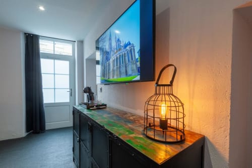 Entrée moderne de l'appartement Bayeuzen avec télévision écran plat affichant un château, lampe cage décorative et porte vitrée donnant sur