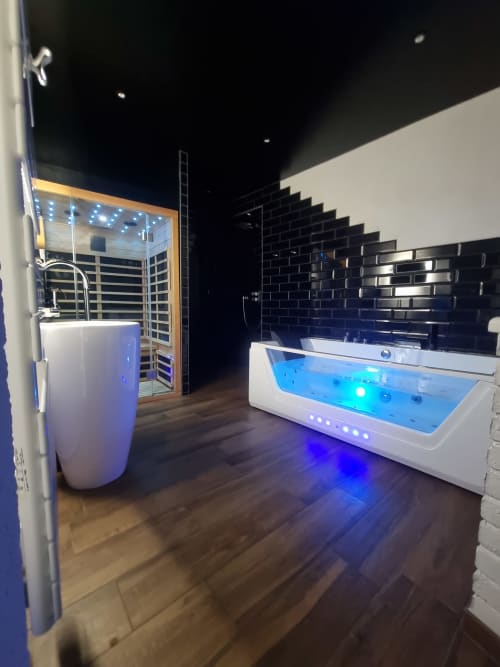 Salle de bains spa luxe au Bayeuzen B&B avec baignoire balnéo illuminée et cabine sauna infrarouge équipée d'équipements modernes