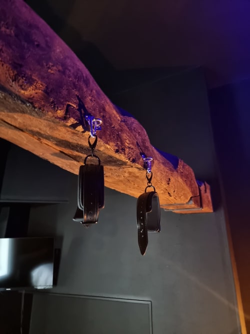 Poulies décoratives suspendues à une poutre en bois rustique avec éclairage ambiant violet dans la suite Le Jardin de la villa Bayeuzen
