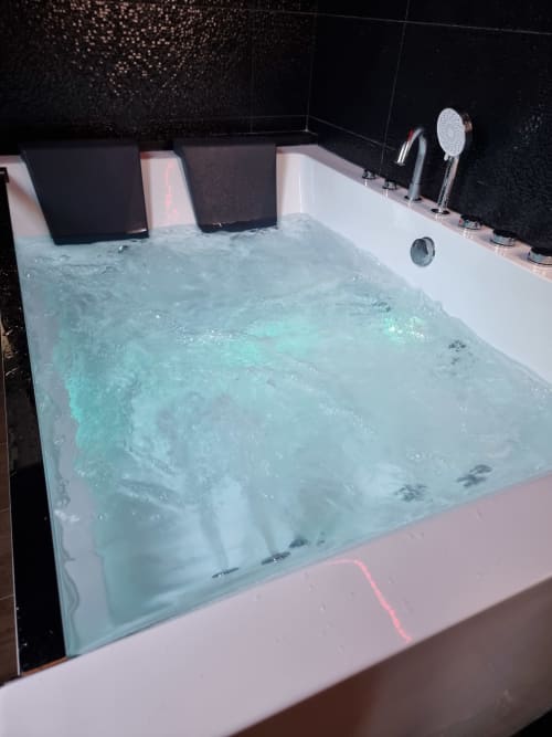Baignoire de luxe avec jets d'eau et eau bleu clair à la villa Le Jardin à Bayeux, France
