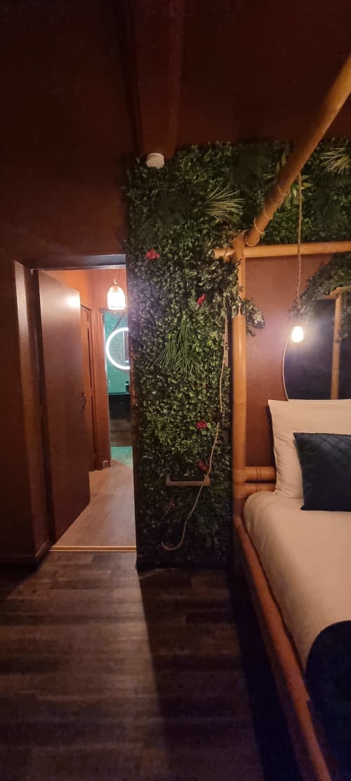 Chambre de la villa La Tropicale à Bayeux avec cloison végétale, poutres en bois et éclairage ambiant