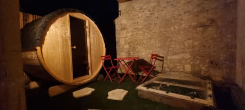 Sauna en forme de tonneau avec chaises rouges et cour en pierre à l'hôtel boutique Bayeuzen à Bayeux, France