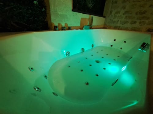 Baignoire d'hydrothérapie illuminée avec jets et éclairage turquoise à la villa La Tropicale de l'hôtel-boutique Bayeuzen, Bayeux