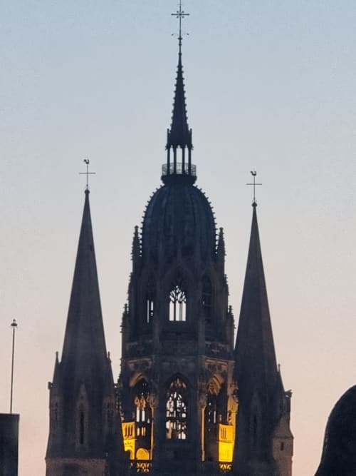 Les flèches gothiques de la cathédrale de Bayeux illuminées au crépuscule, vue depuis la villa La Tropicale