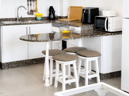 Cocina moderna con encimeras de granito, muebles blancos y zona de bar en apartamento de Tenerife