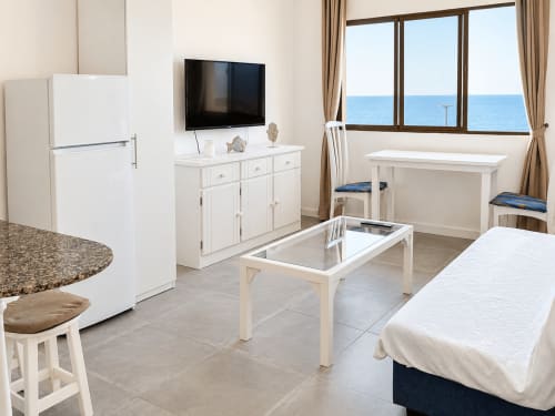 Moderno apartamento en Tenerife con vistas al mar, mobiliario blanco, cocina, comedor y balcón frente al océano