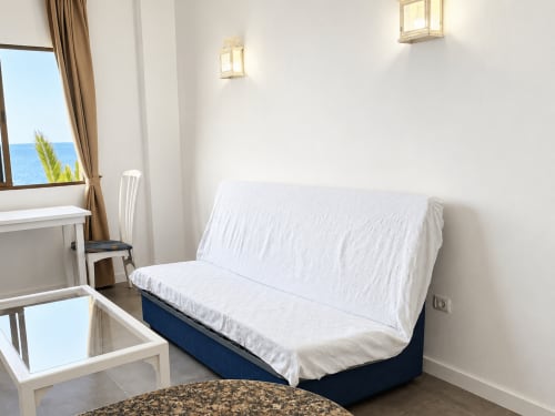 Luminoso apartamento frente al mar en Tenerife con vista oceánica, sofá cama blanco, escritorio y ventanas al océano