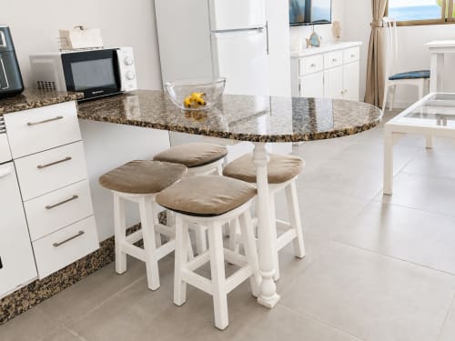 Cocina moderna con encimera de granito, taburetes blancos y vistas al mar en apartamento de Tenerife
