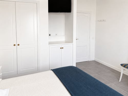 Moderno dormitorio con muebles blancos, TV mural y vistas al mar en apartamento de Tenerife