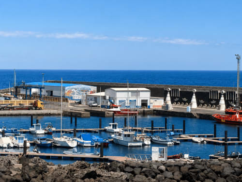 Marina con barcos pesqueros azules e instalaciones portuarias con vista al mar en Santa Cruz de Tenerife