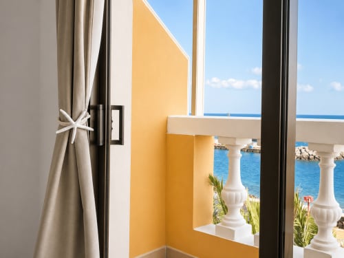 Vista del balcón al Mar Mediterráneo desde el apartamento Restinga La Playa en Tenerife, con paredes amarillas y columnas blancas
