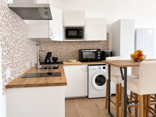 Cocina moderna con azulejos geométricos en el salpicadero, encimeras de madera, lavadora, mesa de comedor y sillas en Restinga La