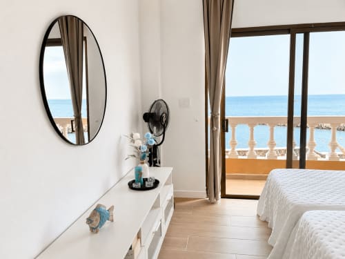 Dormitorio luminoso con vistas al mar, camas gemelas, espejo ovalado, ventilador y balcón con vista al Mediterráneo en Tenerife