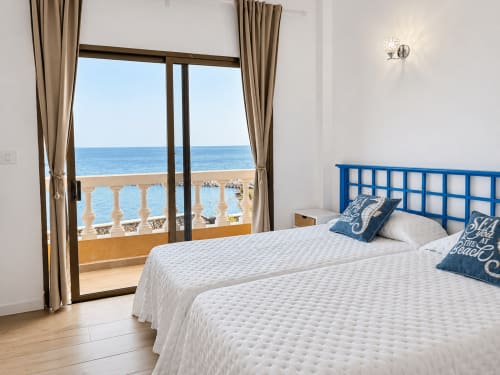 Dormitorio luminoso con cabecero azul, camas gemelas y balcón con vistas al mar y playa en apartamento de Tenerife