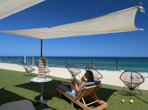 Woman relaxing on beachfront lounge at Vidasoul in La Vinorama, Mexico, under sail shade with ocean view