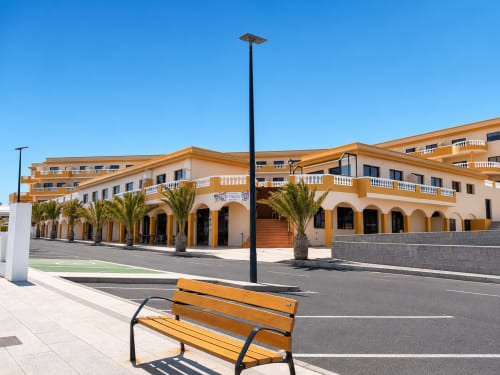 Edificio de apartamentos amarillo frente al mar en Santa Cruz de Tenerife con palmeras, terraza moderna y vistas al océano