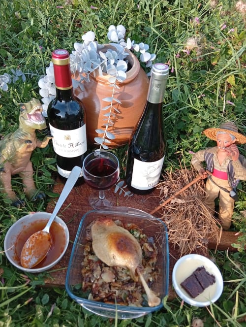 Pique-nique en plein air à la Maison d'hôtes Prehistogite avec vin, charcuterie et figurines décoratives dans le jardin à Saint-Genies, France.