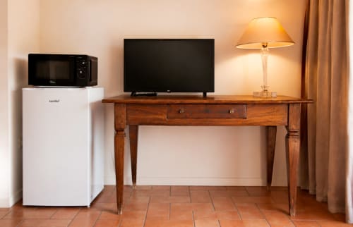 Camera d'hotel a Corte delle Giuggiole con scrivania in legno, TV, lampada, frigorifero e forno a microonde in Suite Familiare Le