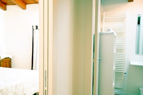 Bagno moderno a Corte delle Giuggiole BnB con portasciugamani bianco, piastrelle verdi e radiatore riscaldante