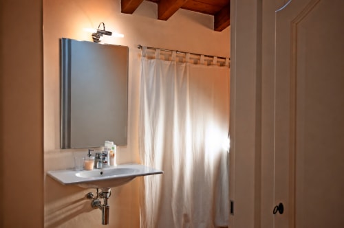 Bagno moderno con lavabo bianco, specchio e tenda doccia presso la Corte delle Giuggiole B&B a Cologna Veneta