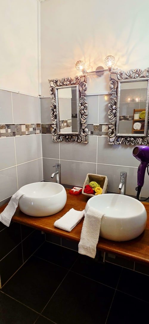 Salle de bain élégante au gîte Le Nid De Bellemont à Trois-Rivières avec vasques doubles, miroirs ornés et décoration raffinée