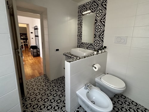 Bagno moderno a Domus Caecilia Roma con piastrelle a motivi bianco e nero, lavabo da appoggio, bidet e wc
