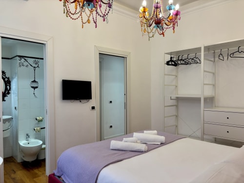 Camera da letto moderna presso Domus Caecilia Roma con letto, bagno ensuite, armadio, lampadari colorati e televisore