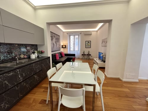 Zona pranzo di moderno appartamento a Roma con cucina, tavolo bianco e soggiorno in Domus Caecilia via Cola di Rienzo