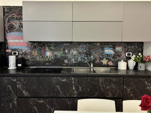 Cucina moderna nell'appartamento Domus Caecilia a Roma con piani in marmo nero, alzatile in lavagna e mobili bianchi