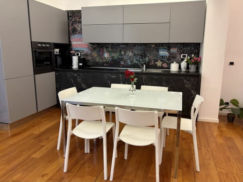 Moderna zona cucina-pranzo all'Domus Caecilia Roma con tavolo bianco, sedie, lavagna nera e grigio