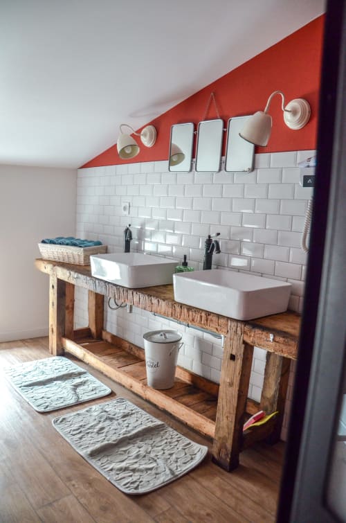 Modern bathroom vanity with dual sinks, white subway tiles, and red accent wall at La Maison d'Augustin family apartment in