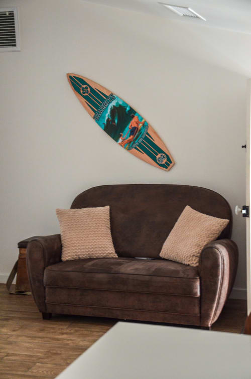 Brown couch with beige pillows and vintage surfboard wall art in La Maison d'Augustin apartment, Mont-de-Marsan