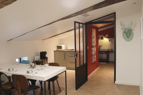 Modern open-plan apartment at La Maison d'Augustin with dining area, kitchenette, and red-walled bathroom in Mont-de-Marsan