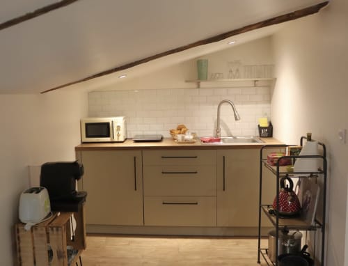 Modern kitchenette in La Maison d'Augustin family apartment with cream cabinetry, white subway tile backsplash, and stainless