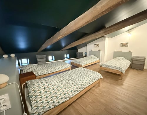 Spacious bedroom with three wooden beds, exposed beams, and modern amenities at La Maison d'Augustin BnB in Mont-de-Marsan