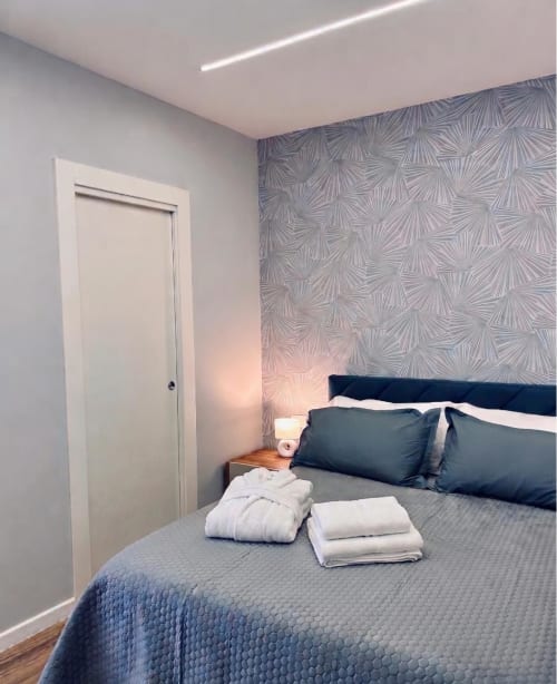 Camera moderna presso Anima Est Napoli con parete decorata, letto matrimoniale e porta bianca