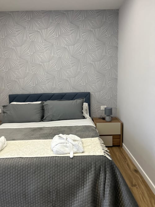 Camera moderna all'Anima Est B&B di Napoli con letto matrimoniale, testata scura, carta da parati geometrica e comodino in legno