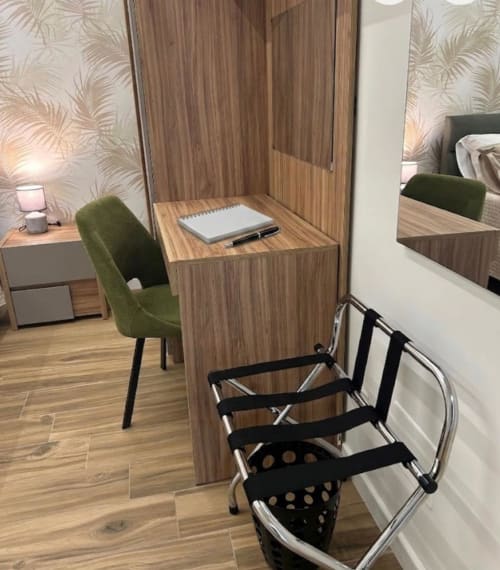 Moderna zona di lavoro presso Anima Est Naples B&B con scrivania in legno, sedia verde e sedie nere impilate