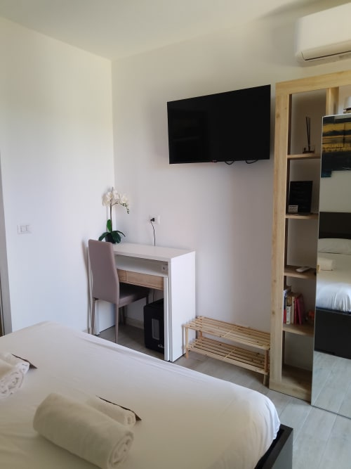 Moderna camera d'hotel a Sissi presso Queen Hotel Campofilone con TV a schermo piatto, scrivania bianca, sedia, scaffali in legno e letto con