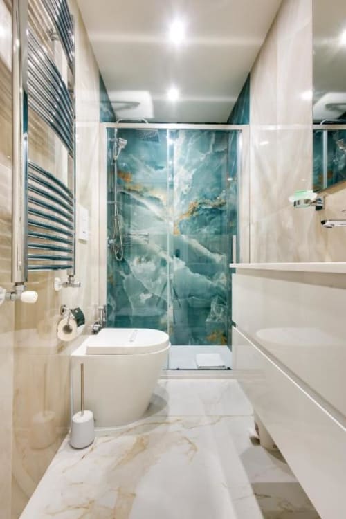 Bagno moderno dell'hotel Domus Praeclara Merulana di Roma con doccia in marmo turchese, sanitari bianchi, scaldasalviette e