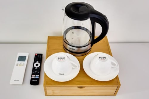 Set di comfort della camera con bollitore elettrico, tazze, telecomando e termostato su vassoio in legno presso Domus Praeclara Merulana