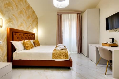 Camera Deluxe King del Domus Praeclara Merulana a Roma con letto imbottito arancione, carta da parati dorata e comfort moderni