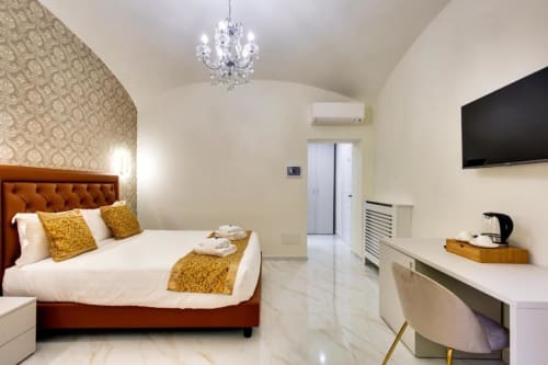 Camera Superior King presso Domus Praeclara Merulana a Roma con elegante letto, lampadario di cristallo, TV a schermo piatto e arredamento moderno